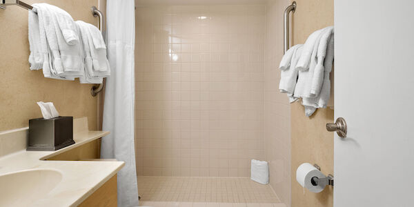 A bathroom with a tiled shower, towels, and a tissue box.