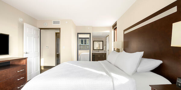 A hotel room with a large bed, dresser, and TV