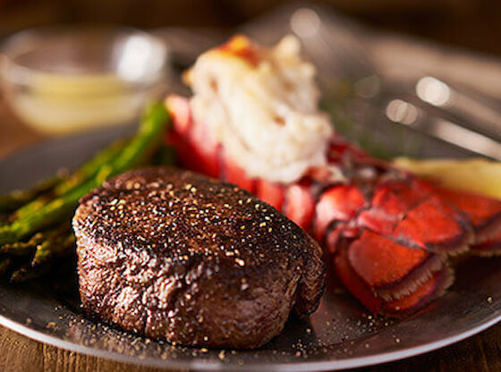 A plate of food with a steak, lobster, and asparagus.