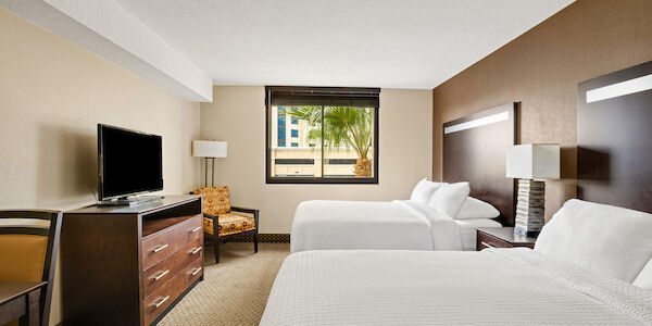 A standard hotel room with two beds, a TV, and a window.