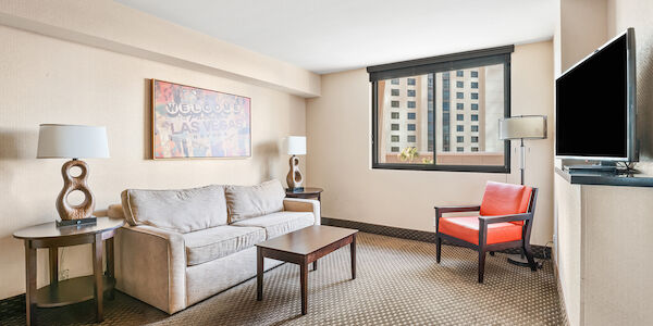 A hotel suite with a sofa, coffee table, chair, and TV