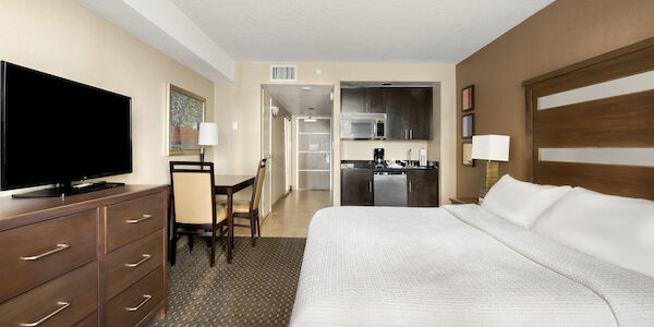A hotel suite with a kitchenette, dining area, and a large bed