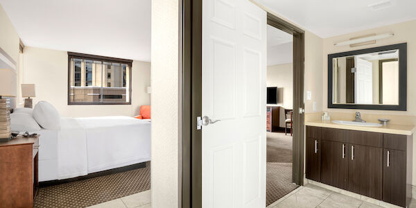 A hotel room with a bed, bathroom, and doorway.