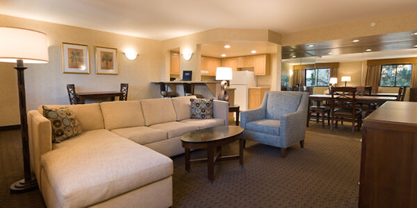 A spacious living room with a sofa, armchair, coffee table, and dining table.