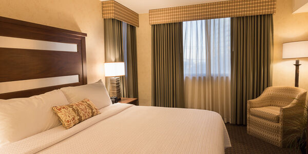 A hotel room with a bed, chair, and window