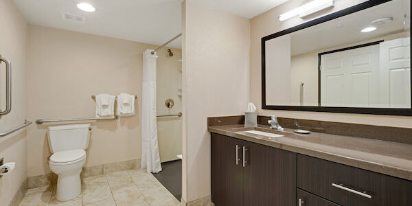 A bathroom with a toilet, shower, sink, and cabinet.