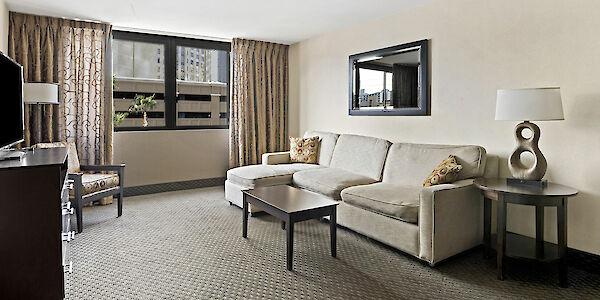 A seating area with a sofa, coffee table, TV, and mirror.