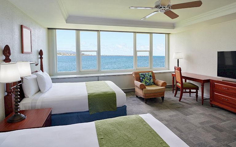 A hotel room with two beds, a large window, and a TV