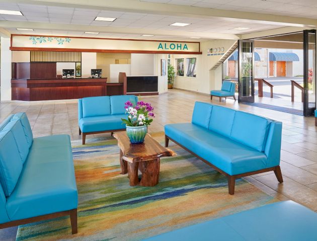 A lobby with blue sofas, a wooden coffee table with flowers, and a reception desk in the background.